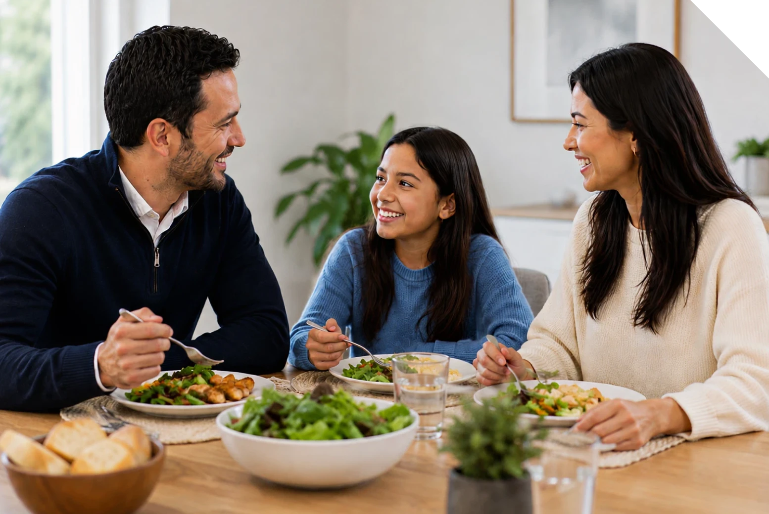 A father, mother, and daughter share a meal together at the dinner table.