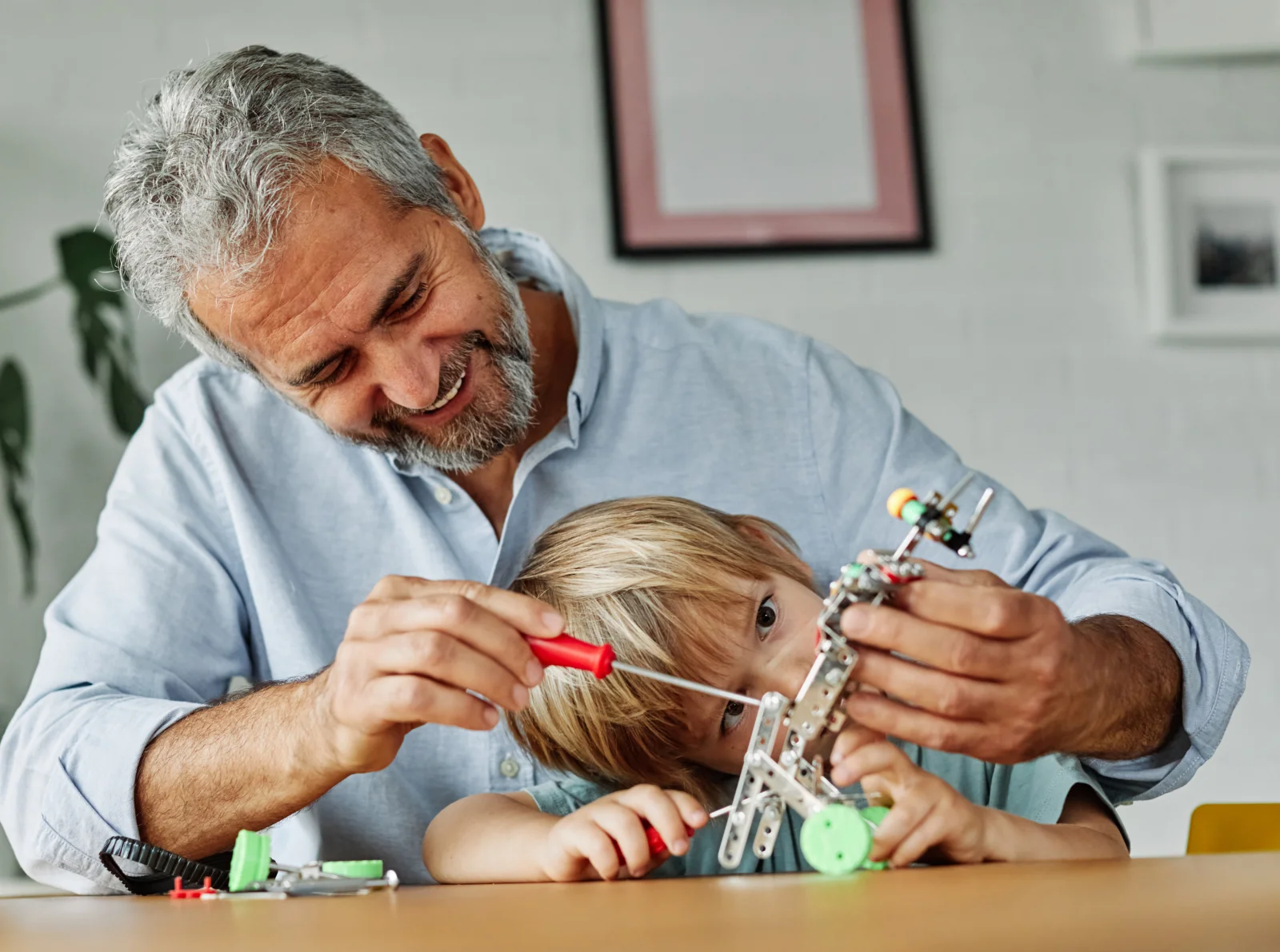 A father helps his young son with a hands-on mechanical project.