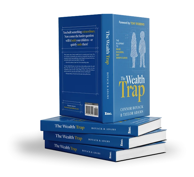 A stack of hardcover copies of The Wealth Trap by Connor Boyack and Taylor Adams.